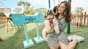 A woman holds a dog beside pet friendly zone sign in one of Vida Hotel’s pet friendly parks.