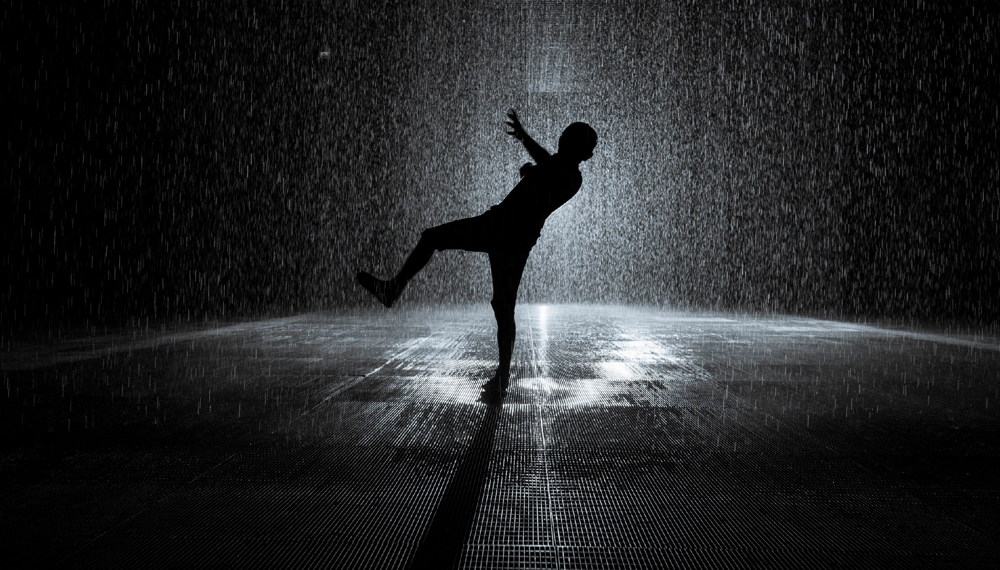 A person dances in the rain in the immersive Rain Room in Sharjah